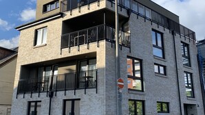 Een meerlaags gebouw met een plat dak en balkons, met een bord dat parkeren verbiedt.