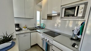 Una cocina moderna con armarios blancos, microondas integrado, estufa y lavavajillas.