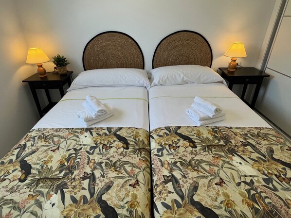 Una cama doble con sábanas de estampado floral, dos almohadas y dos mesitas de noche con lámparas.