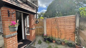 A brick house with a wooden door, a wooden fence, and several potted plants. - Private Studio Flat Great Location in Manchester (Manchester)