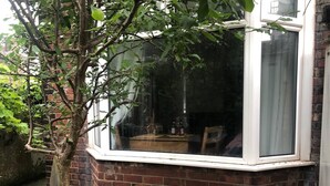 A corner room with a brick wall and a window overlooking a garden. - Private Studio Flat Great Location in Manchester (Manchester)