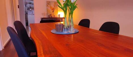 A dining area with a wooden table, four chairs, and a vase with white flowers.