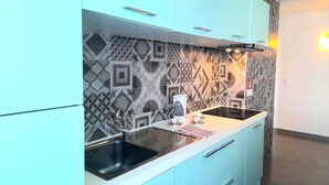 Una cocina moderna con armarios azul claro, un lavamanos negro y azulejos decorativos en la pared.