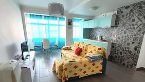 Una sala moderna con un sofá, una mesa de comedor y un rincón americano.