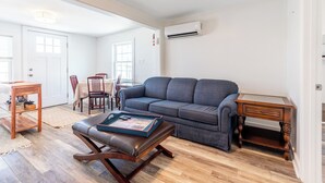 Ein geräumiges Wohnzimmer mit grauem Sofa, Couchtisch aus Holz und einem kleinen Holztisch.
