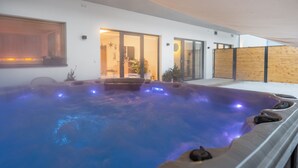 A modern indoor swimming pool with a glass enclosure, a wooden deck, and a view of the adjacent room. - zeitlang by Rösslwirt (Lam)