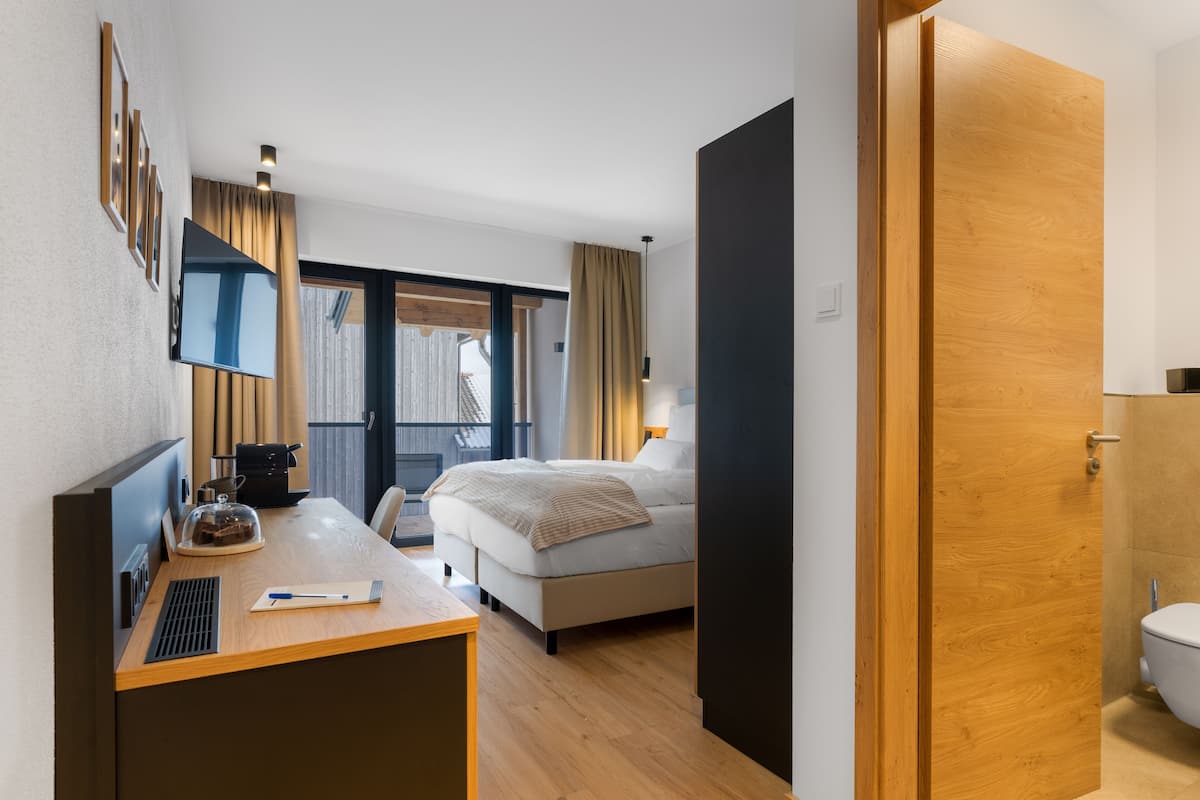 Ein Hotelzimmer mit Bett, Schreibtisch mit Computer, Fernseher und Bad mit Toilette.