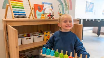 Children can play and learn in this room with a bookshelf and wooden shelves filled with toys and books.