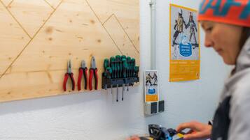 Een werkplaats met gereedschap aan de muur en iemand die aan een apparaat werkt.