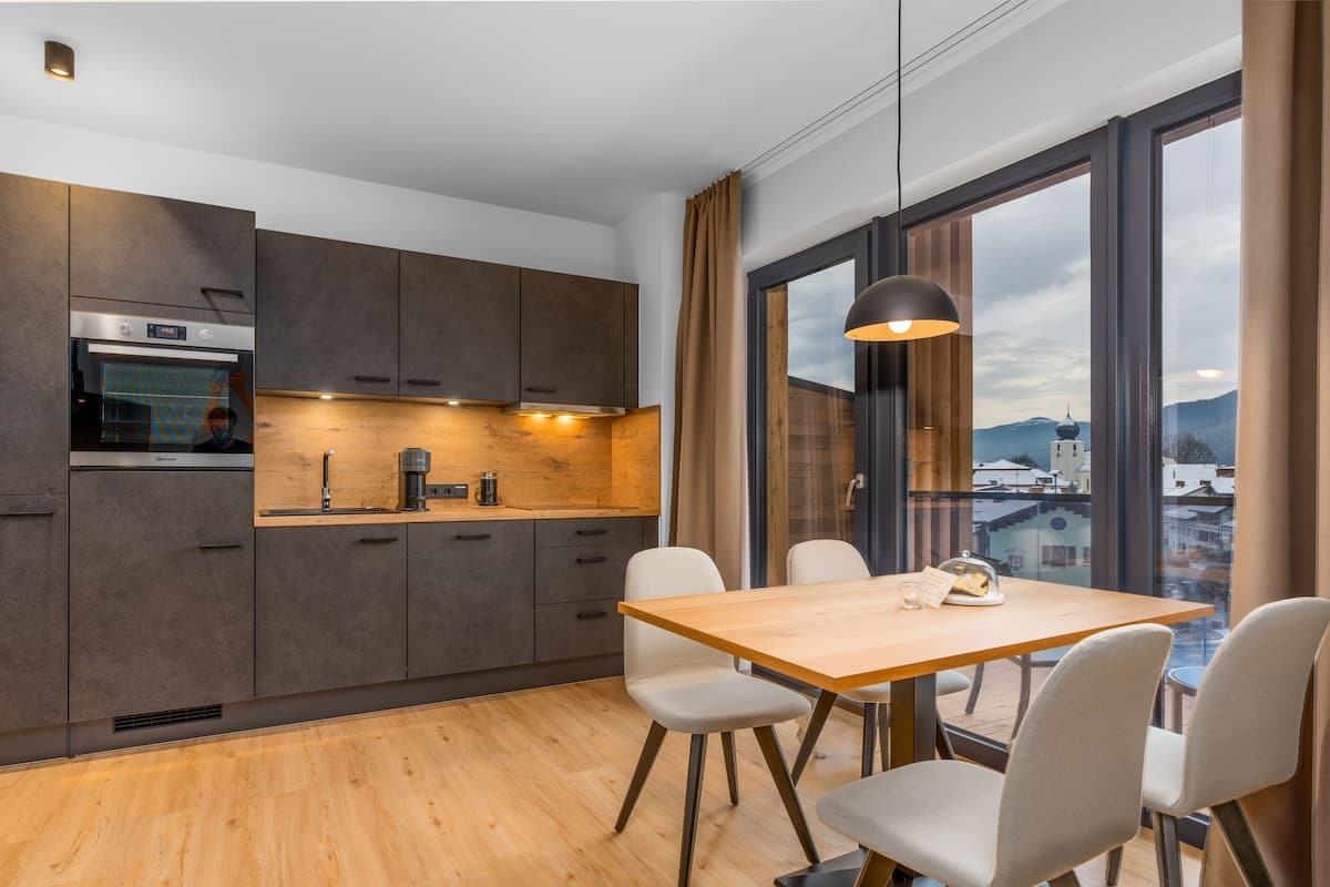 Eine moderne Küche mit dunklen Schränken, einer Holz Arbeitsplatte und einem Essbereich mit Tisch und Stühlen.
