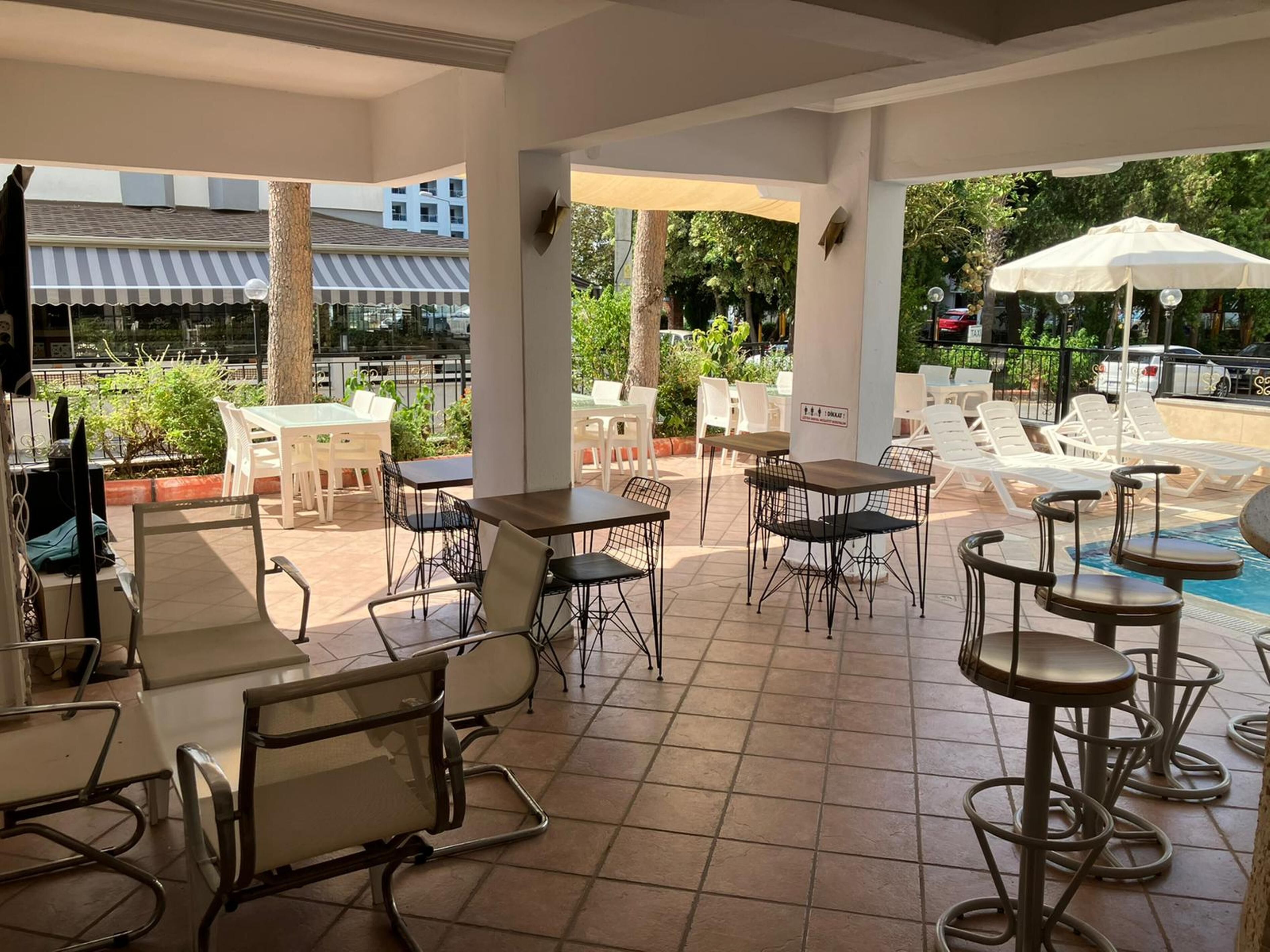 An outdoor patio area with tables and chairs, a pool, and umbrellas.