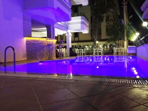 An outdoor swimming pool with a stone wall and a metal railing. - Christina Apart Otel (Alanya)