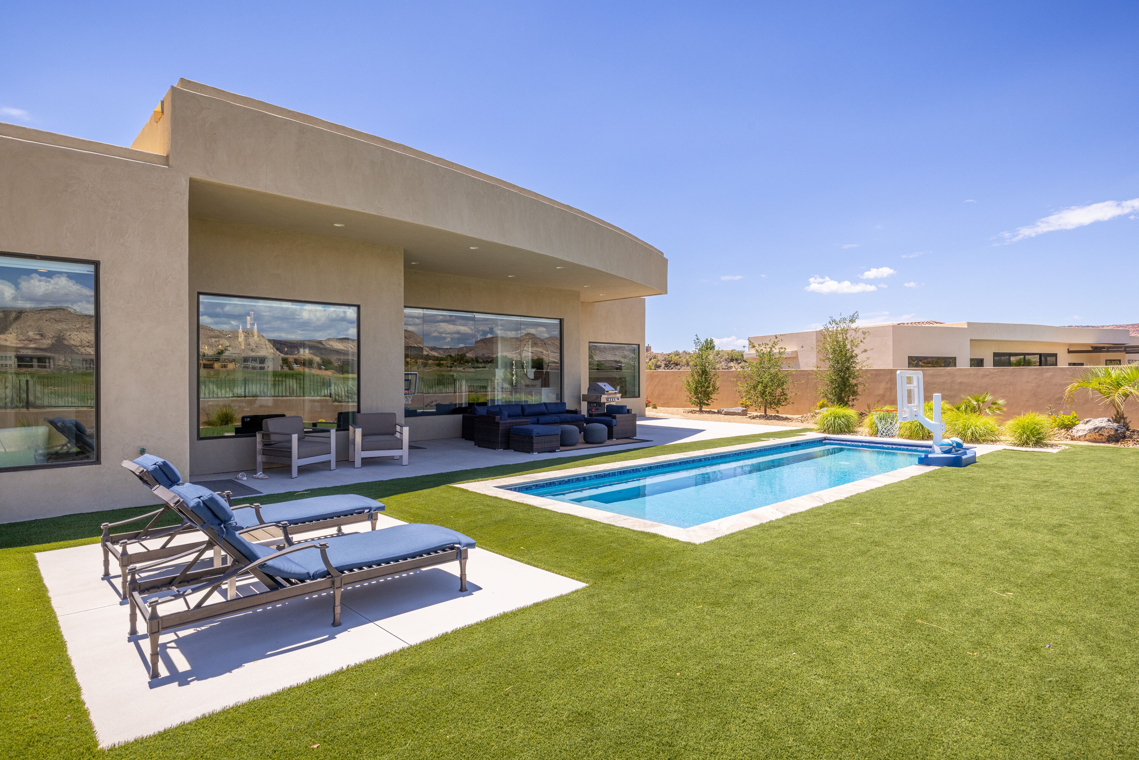 Une maison moderne dotée d’une piscine, d’un espace salon extérieur et d’une pelouse bien entretenue.