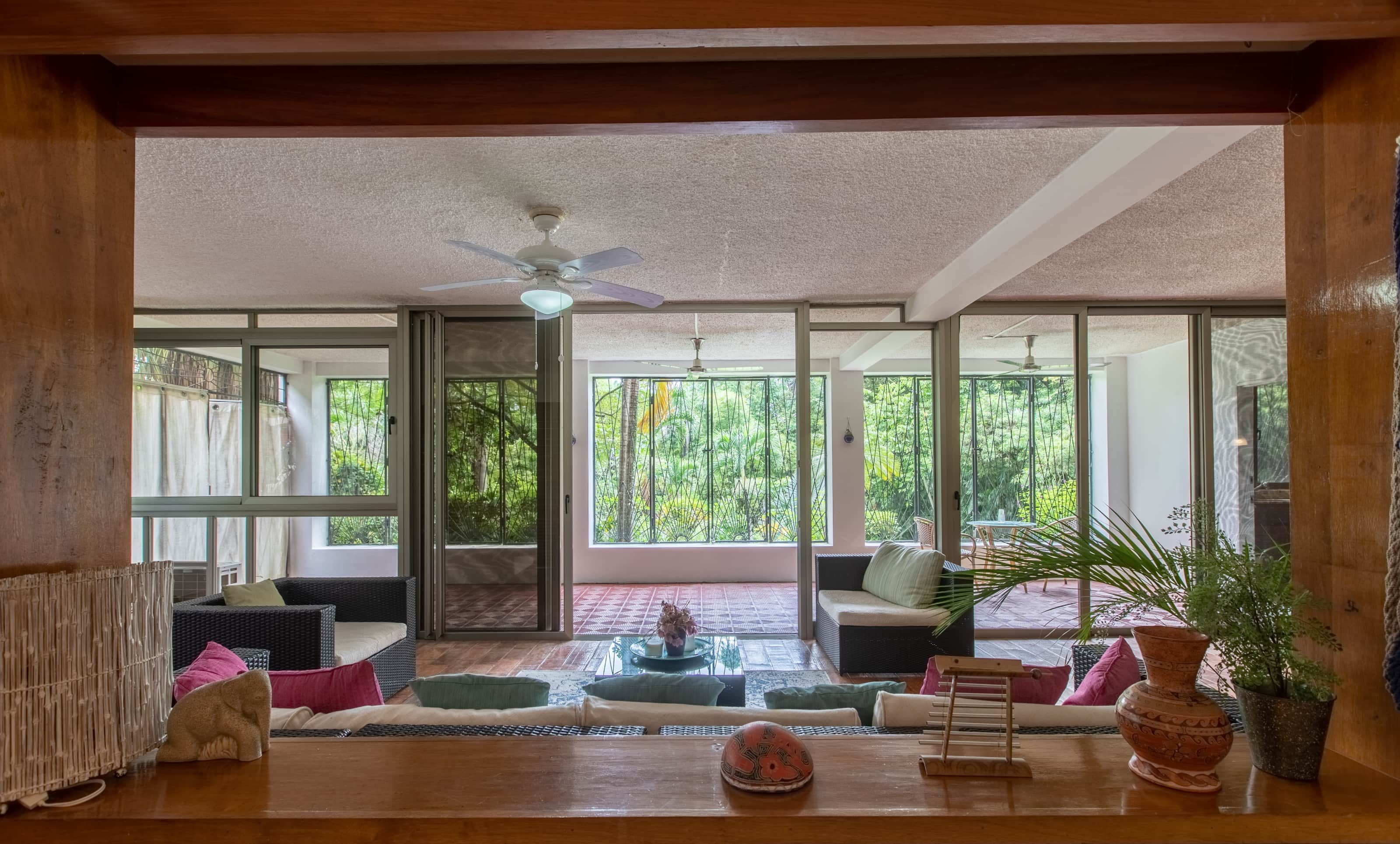 A spacious room with a large sliding glass door leading to an outdoor area, a ceiling fan, and a variety of seating arrangements.