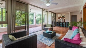 Un vaste espace de vie doté d’une grande porte-fenêtre coulissante donnant sur un patio, d’un ventilateur de plafond et d’un coin repas situé à l’arrière-plan.