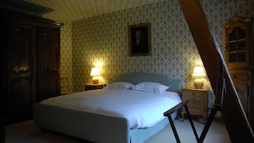 A bedroom with a large bed, two bedside tables with lamps, a wooden wardrobe, and a patterned wallpaper.
