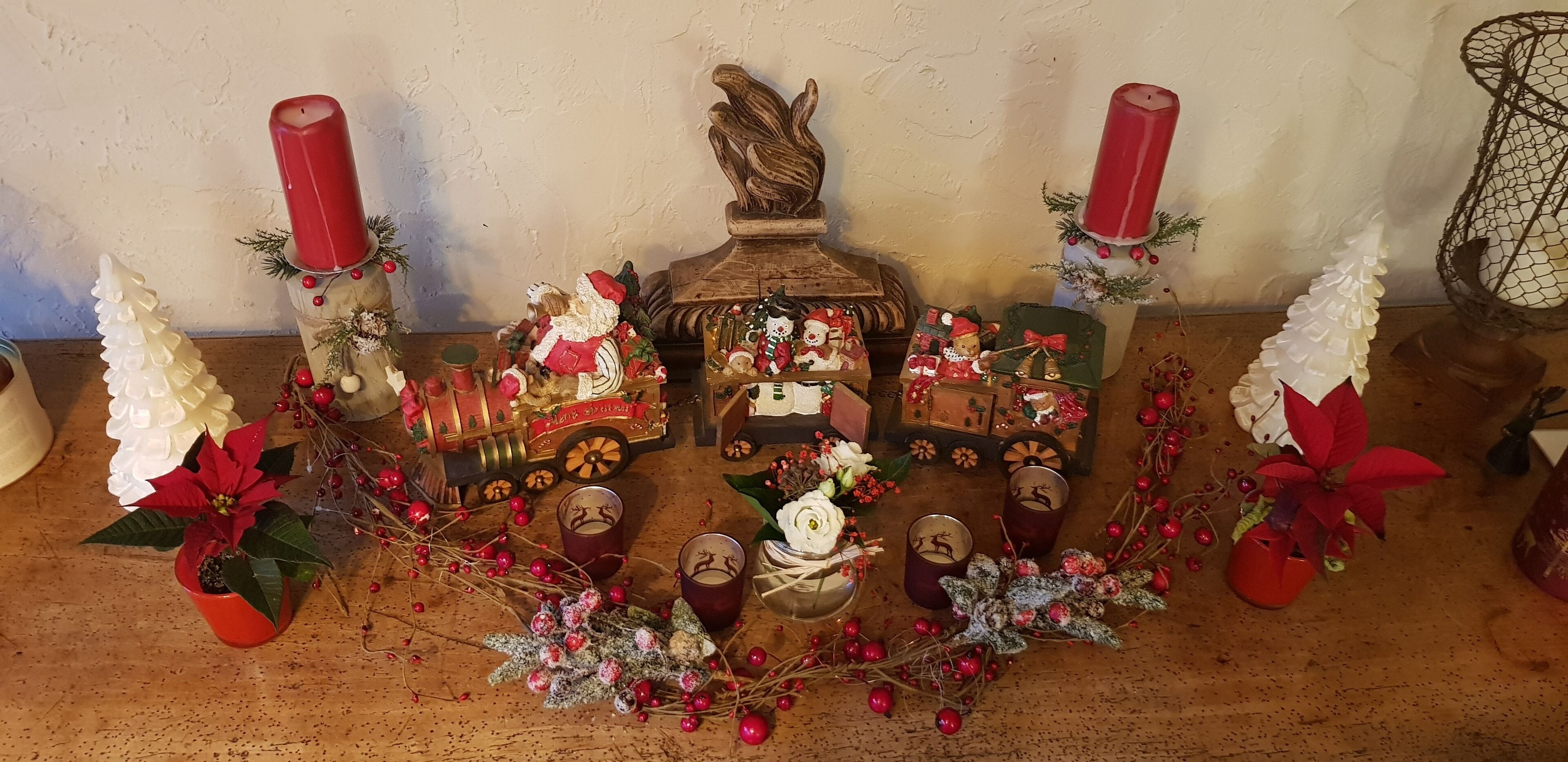 A Christmas display with a train, candles, and poinsettia plants.