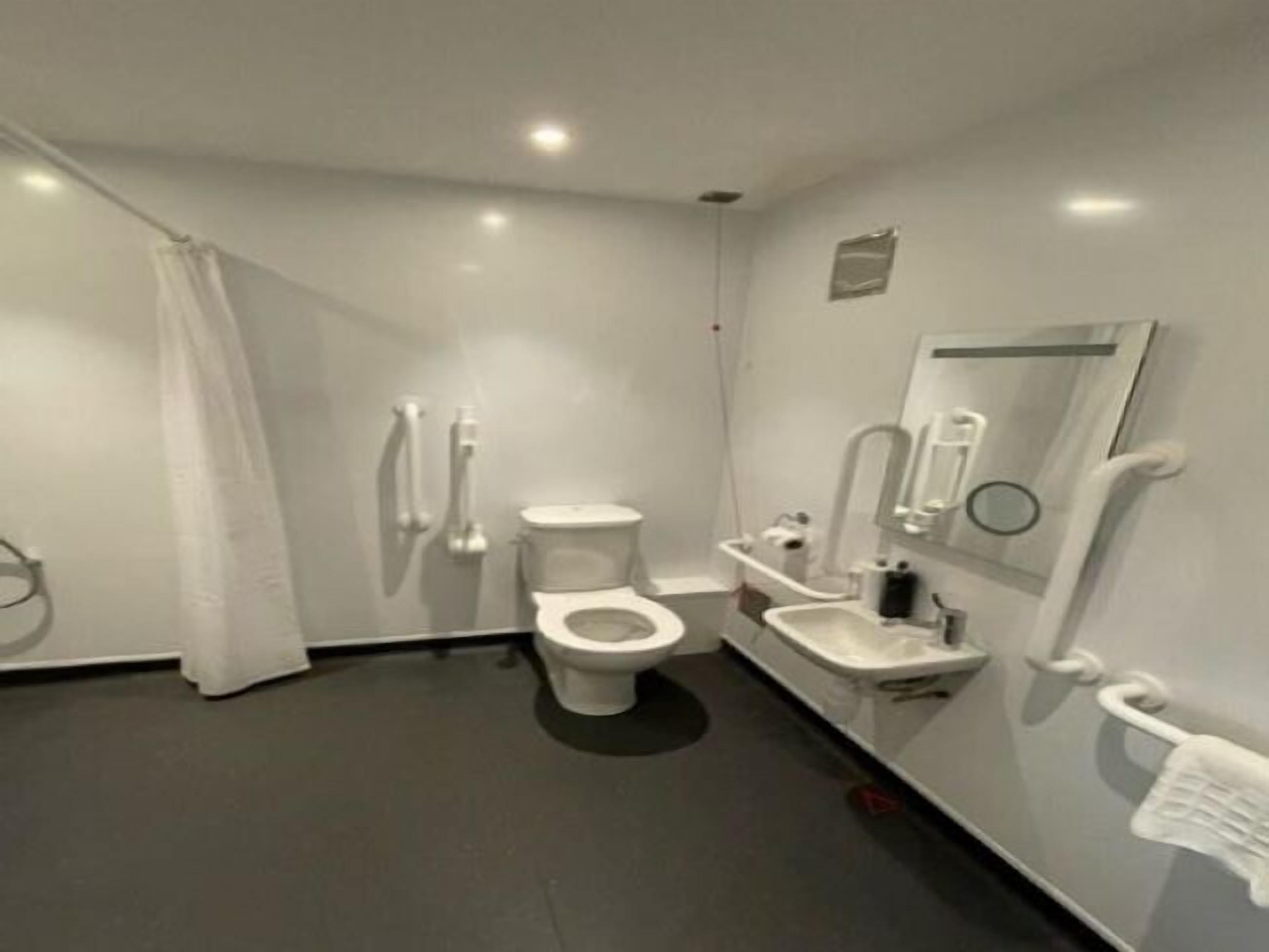 A modern bathroom with a toilet, bidet, sink, and a mirror.