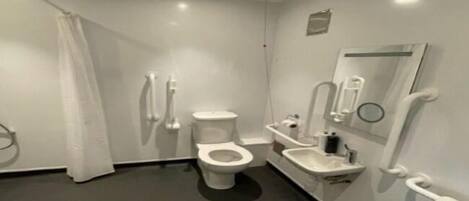 A modern bathroom with a toilet, bidet, sink, and a mirror.