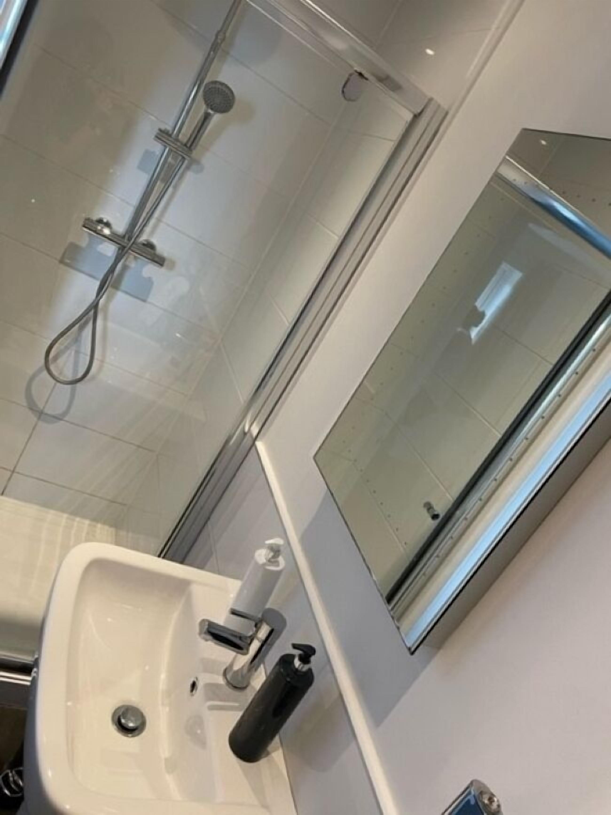 A bathroom with a glass shower enclosure, a sink with a faucet, and a mirror.
