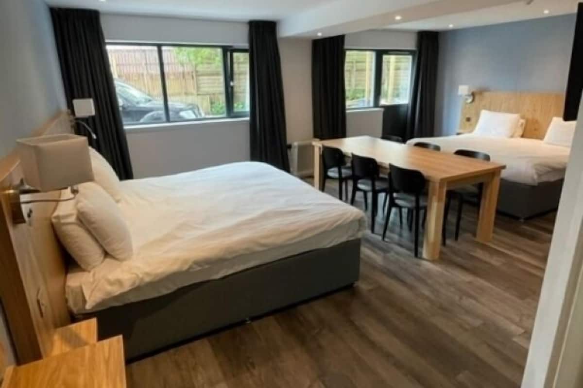 Una habitación de hotel moderna con una cama grande, un escritorio y una mesa de comedor.