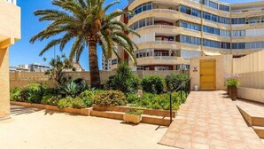 A multi-story hotel with balconies, a palm tree, and a well-maintained garden area. - Inftour President 1 Apartamento (Calp)