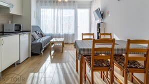 A compact living space with a kitchenette, a sofa, a dining table with chairs, and a TV mounted on the wall. - Inftour President 1 Apartamento (Calp)