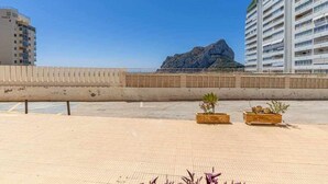 A rooftop terrace with a view of a rocky outcrop and a building with balconies. - Inftour President 1 Apartamento (Calp)