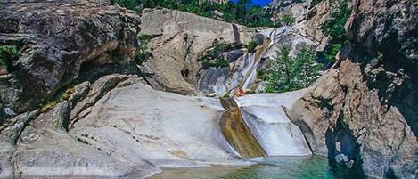 A natural rock formation with a waterfall and clear water.