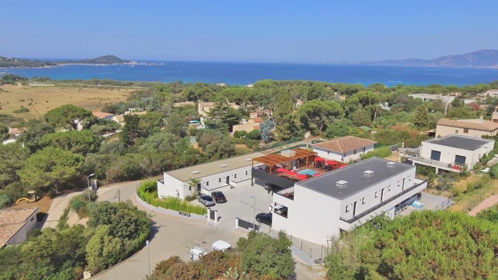 Un quartier résidentiel avec un grand immeuble doté d’un toit plat et d’un espace extérieur abrité.
