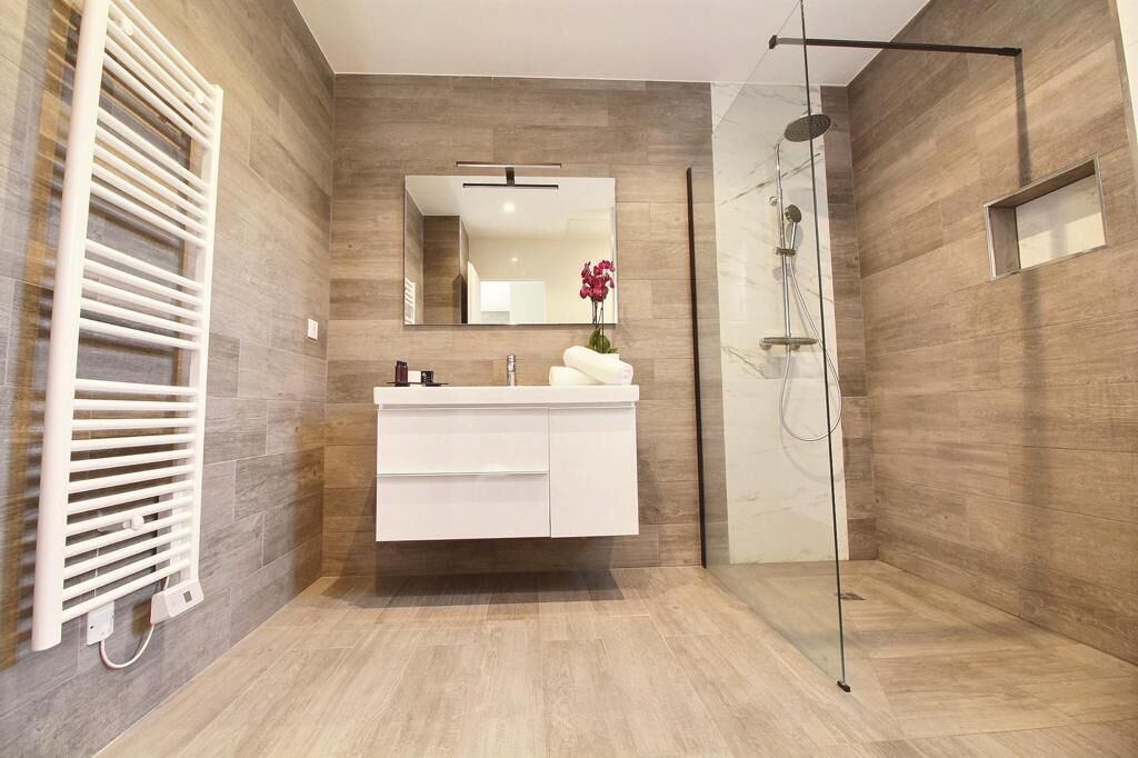 A modern bathroom with a white vanity, a large mirror, and a glass shower enclosure.
