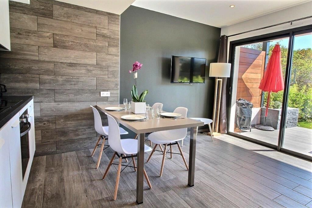 Een moderne eethoek met een houten wand, een tafel voor vier personen en een aan de muur bevestigde televisie.
