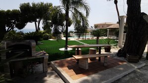 Eine Terrasse mit Grill, einem Holztisch und einer Sitzbank.