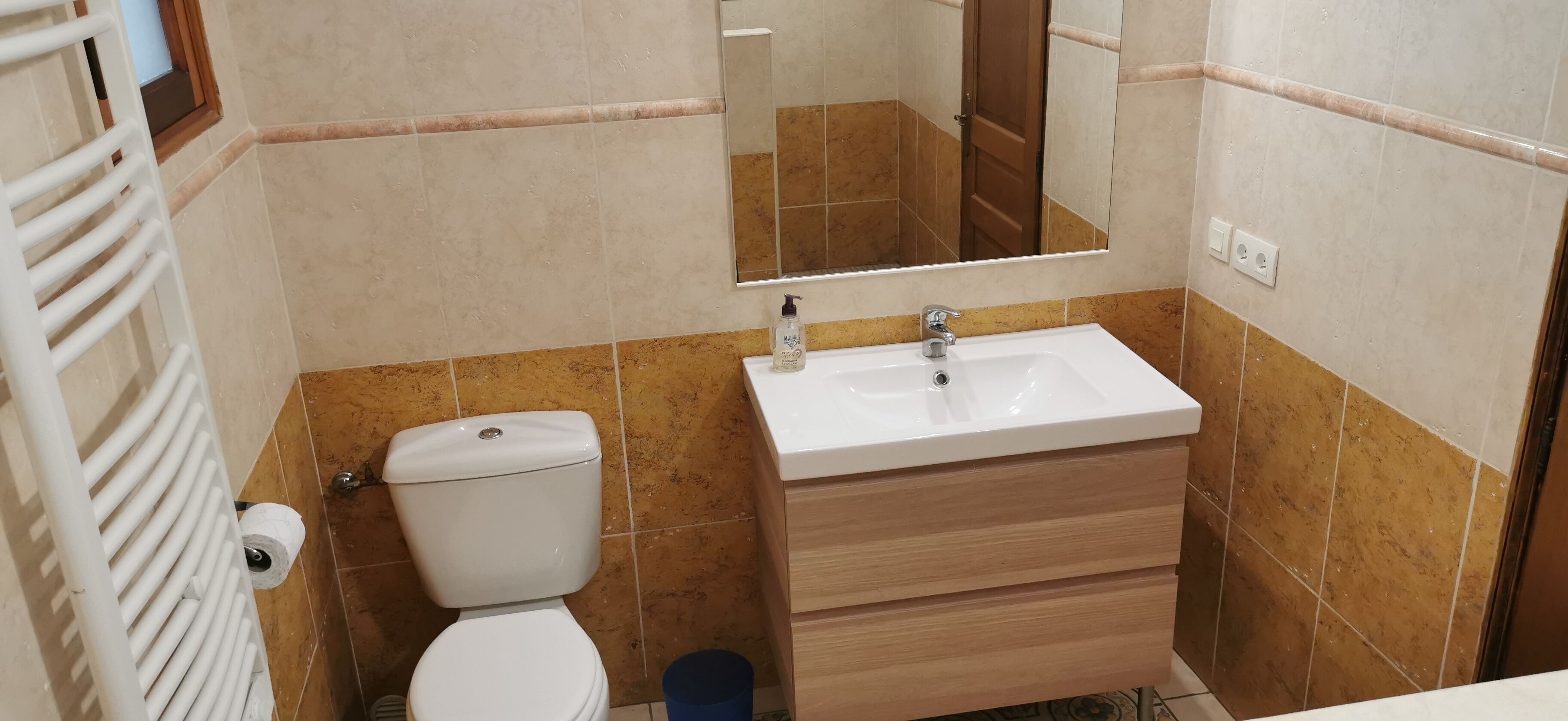 A bathroom with a white sink, a mirror, a toilet, and a towel rack.