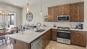 Una cucina moderna con mobili in legno, elettrodomestici in acciaio inossidabile e una grande isola con lavastoviglie.