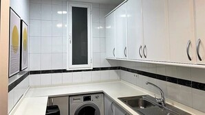 A modern kitchen with white cabinets, a built-in washing machine, and a sink. - Cozy apartment in the Barrio de las Letras in Madrid (Madrid)