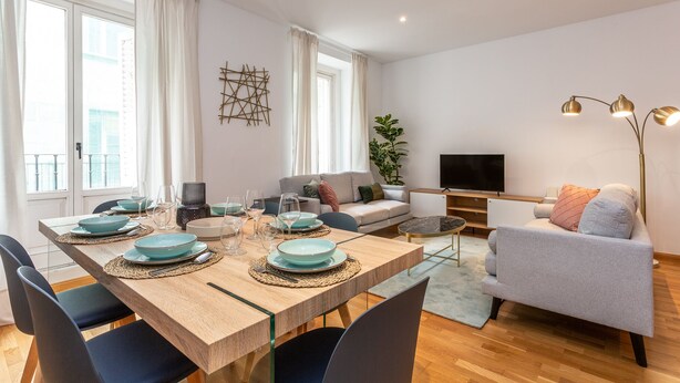 A modern living room with a dining area, a sofa, a TV, and a plant. - Cozy apartment in the Barrio de las Letras in Madrid (Madrid)