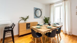 A dining area with a wooden table, black chairs, and a cabinet with a plant. - Cozy apartment in the Barrio de las Letras in Madrid (Madrid)