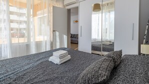 Ein modernes Schlafzimmer mit einem großen Bett, einem Kleiderschrank und einem Spiegel.