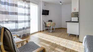 Een kamer met een bed, een bureau, een stoel, een televisie en een koelkast.