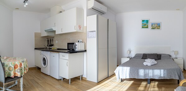 A compact hotel room with a kitchenette, a bed with rolled towels, and a small bedside table. - Inftour President 3 Apartamento (Calp)