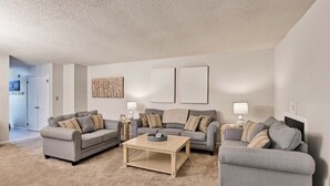 A living room with two grey sofas, a coffee table, and two wall-mounted lamps.