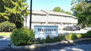 A sign for Westwood at Bethany, a building with a flat roof and a flagpole with an American flag.