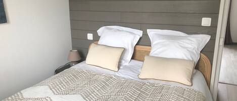 Ein ordentlich gemachtes Bett mit einem gemusterten Bettbezug, einem Kopfteil mit horizontalem Panel-Design und einer Nachttischlampe.