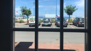 A parking lot with several cars and a beach in the background. - House facing the sea 3* classification (Langrune-sur-Mer)
