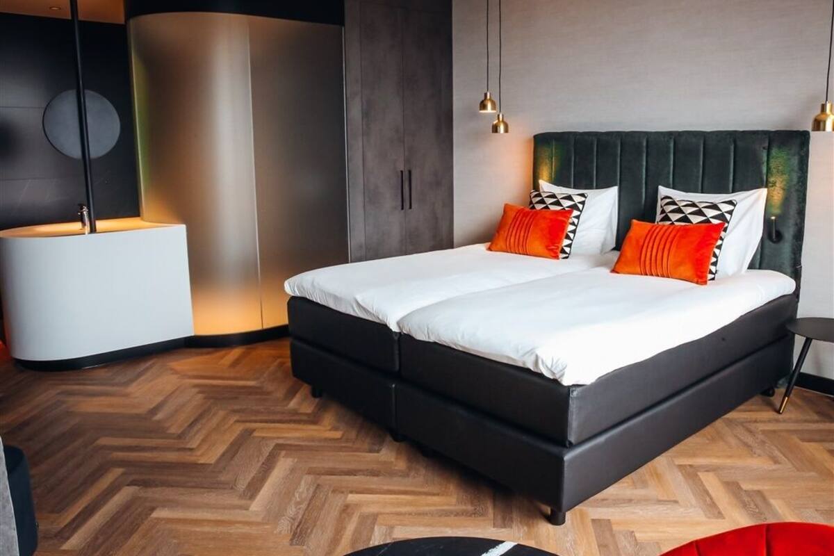 Une chambre moderne avec un grand lit, une table de chevet et un luminaire rond.