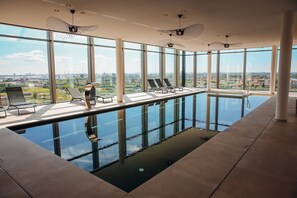 Ein moderner, überdachter Pool mit großen Fenstern und Liegestühlen.