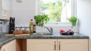 Una cocina con encimera de granito, pileta de acero inoxidable y ventana con vista a la vegetación.