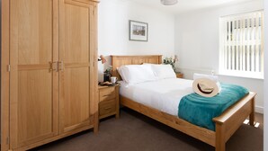 Un dormitorio con cama de madera, mesita de noche, armario y ventana con persianas.
