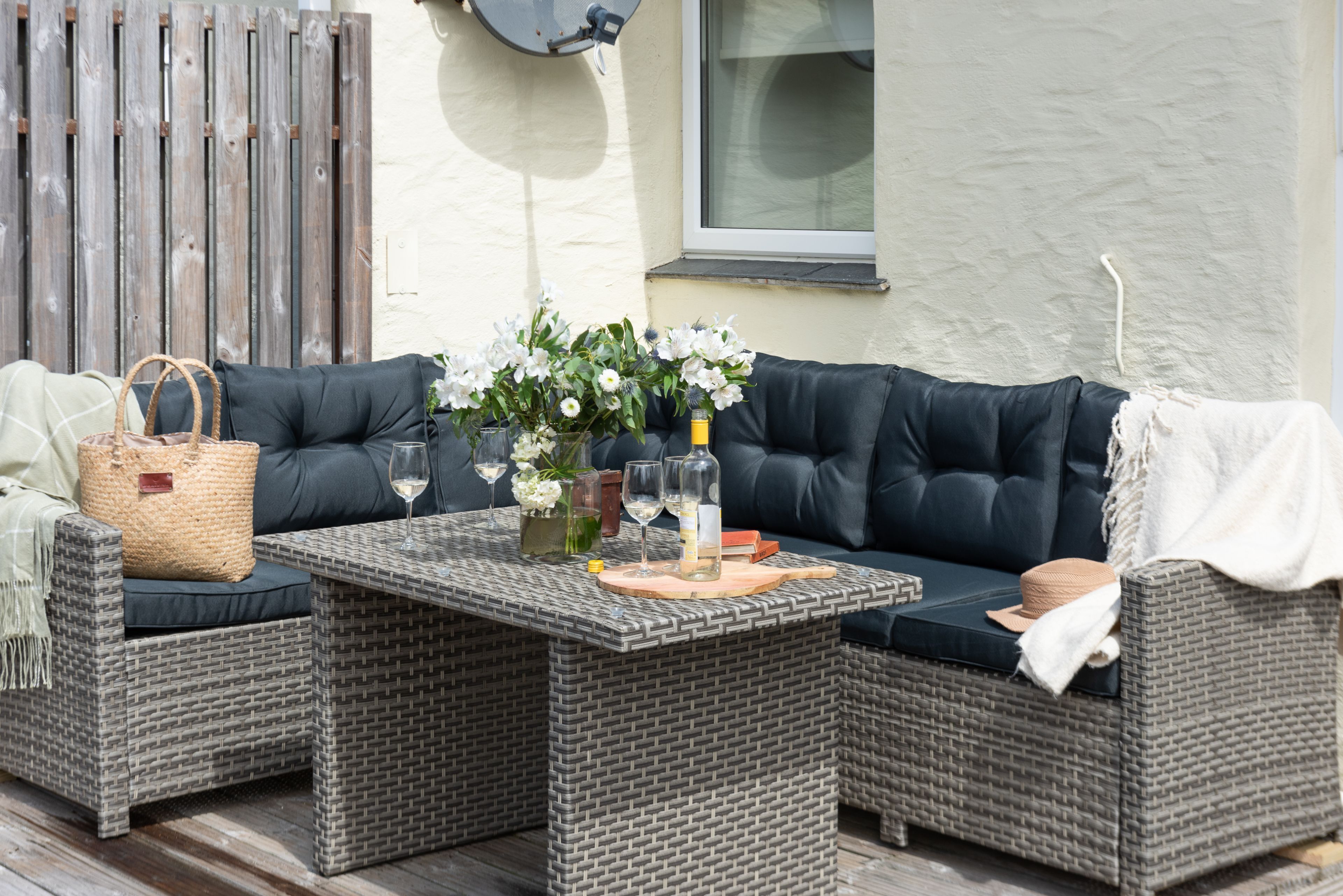 A wicker sofa set with cushions, a glass-top coffee table, and a wicker basket.